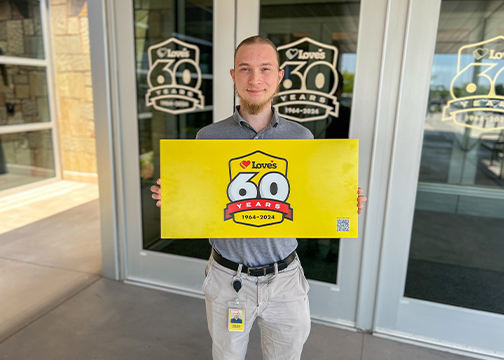 Love's intern, Tristan, holding a 60th Anniversary logo